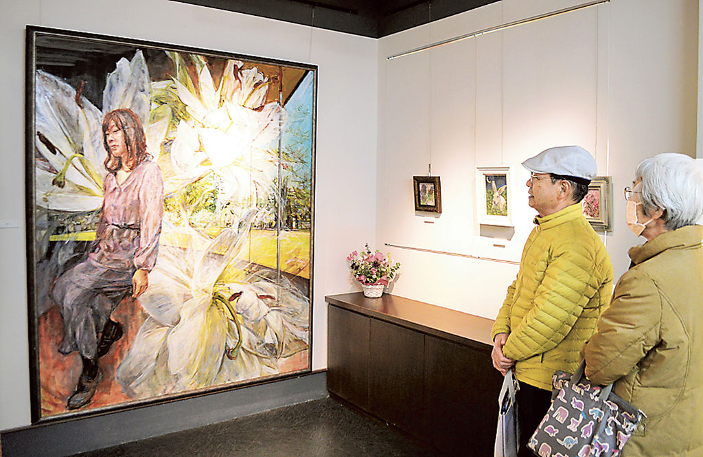 女性とユリを描いた「開花」と題した作品を見る来場者＝静岡市葵区のギャラリー十夢