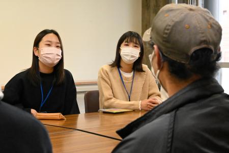 男性と話す西田さん（左）ら香川大の学生＝２０２２年１１月、高松市
