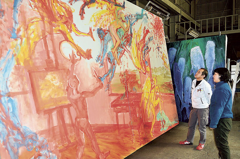 制作中の５００号のキャンバスを見つめる北見美佳さん（右）と工場所有者の男性＝２０２２年１２月下旬、沼津市内