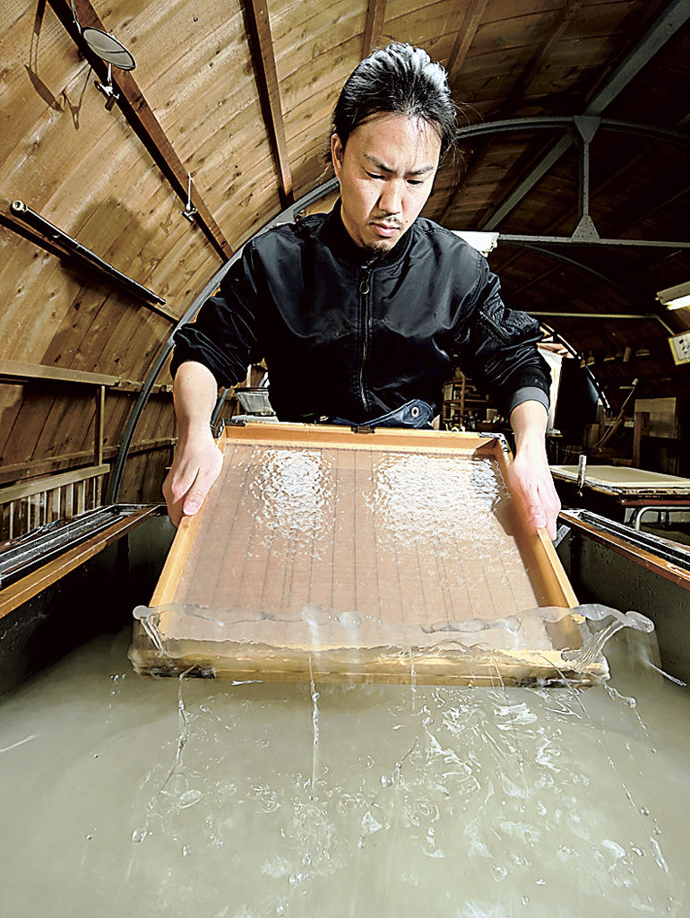 冷たい湧水を使って紙をすく舛田さん＝伊豆市修善寺の紙谷和紙工房