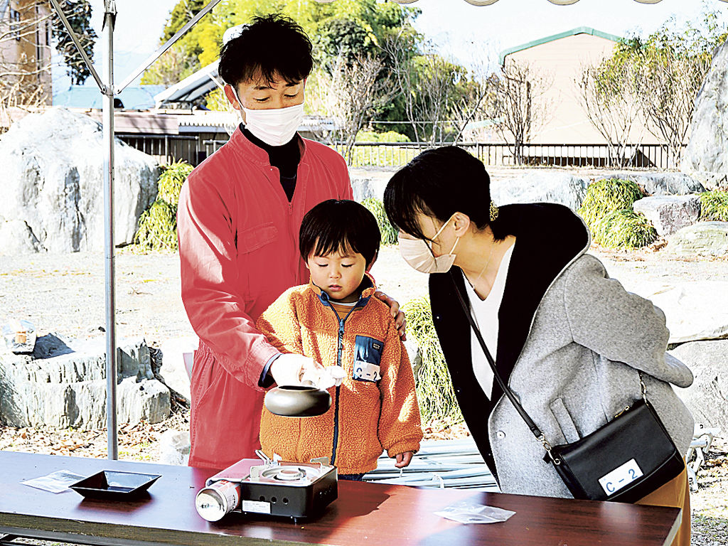 茶レンジャー（左）の指導で茶葉をいる親子＝富士市の旧藤田邸