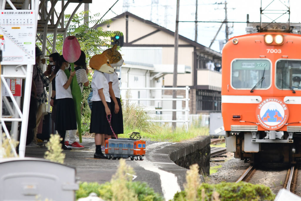 動物のマスクをかぶって撮影する生徒たち。紙製のミニチュア車両「おさがくちゃん」を散歩させている＝９月中旬、富士市の岳鉄本吉原駅