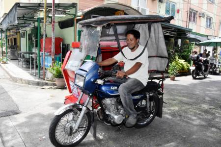 フィリピンのマニラ首都圏で三輪タクシーで働きに出かけるデラバジャヤンさん＝２０２２年９月（共同）