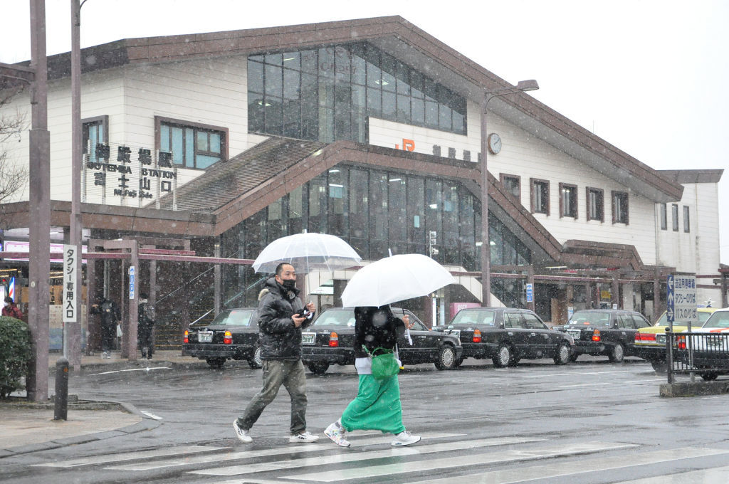 雪が降るＪＲ御殿場駅前を歩く人たち＝２７日午後２時１０分ごろ、御殿場市