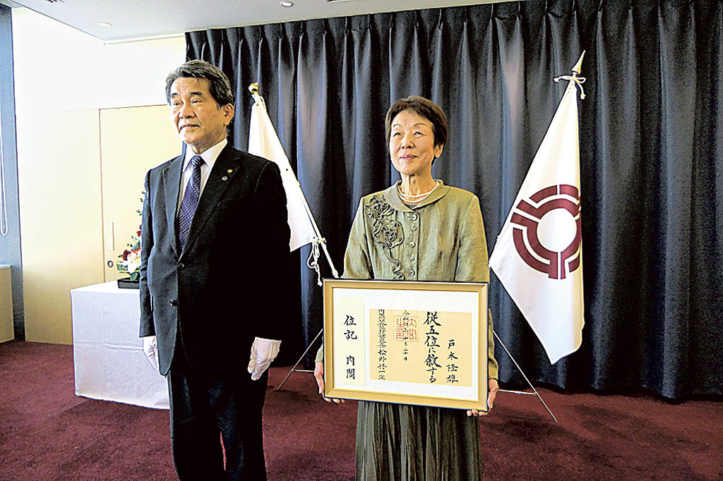中野市長（左）から叙位を伝達された戸本元市長の妻和子さん＝焼津市役所