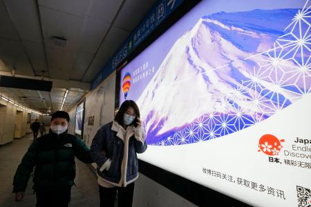北京の地下鉄の駅に掲げられた日本をＰＲする看板の前を歩く人たち＝２９日（共同）