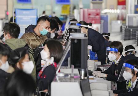 ８日、北京首都国際空港で成田行きの便の搭乗手続きをする人たち（共同）