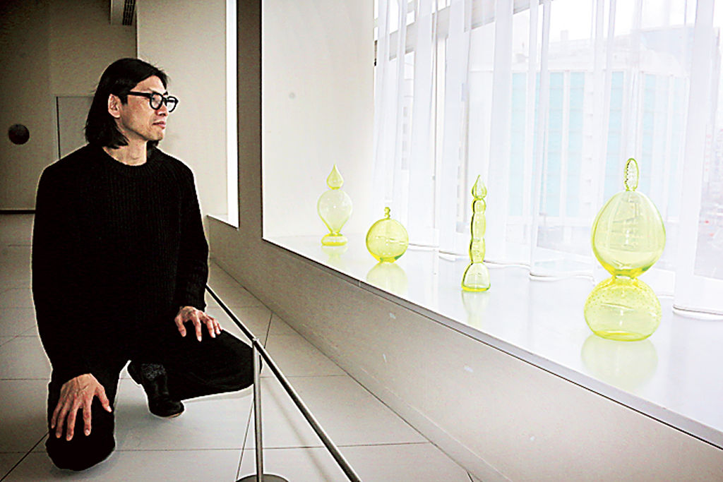 松藤孝一さんとウランガラスを使った作品群。自然光の強弱で色合いが変化する＝静岡市葵区の市美術館