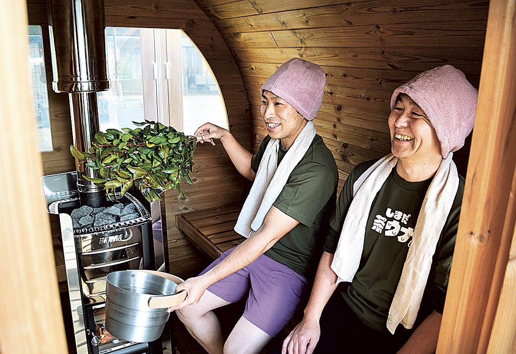 茶樹を使った「茶ヒタ」を手にサウナをＰＲする島田市観光協会の職員ら＝島田市の川根温泉ふれあいの泉