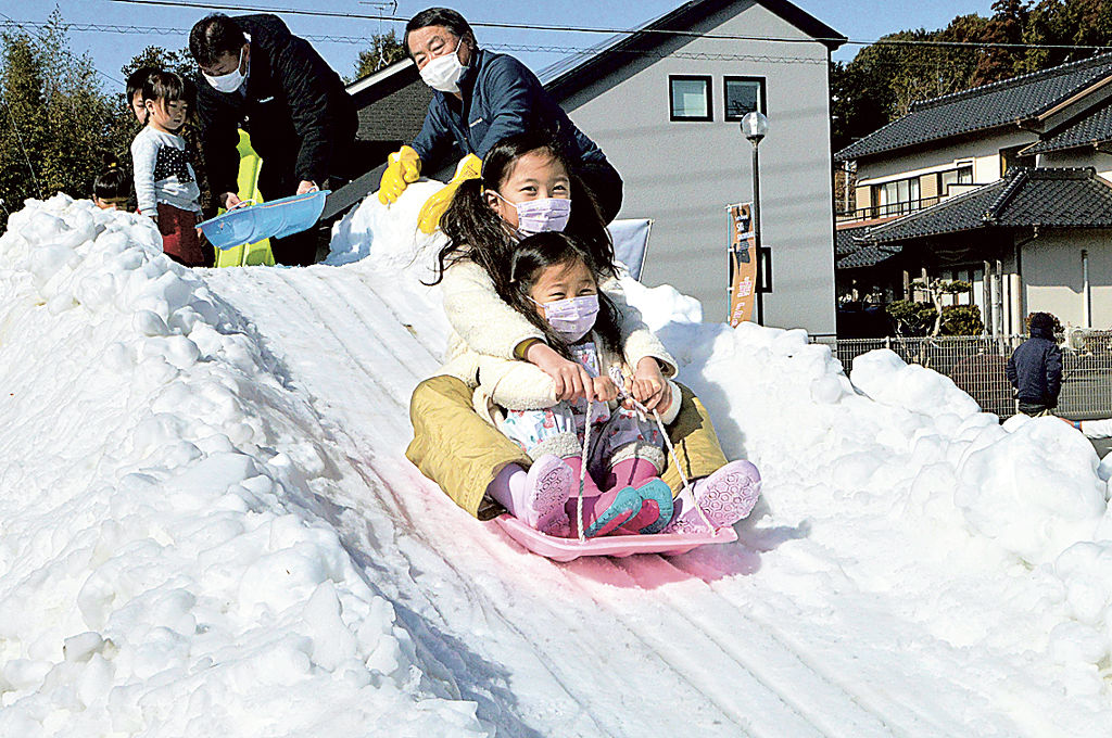 雪の滑り台でそり遊びを楽しむ子どもたち＝菊川市の六郷地区センター