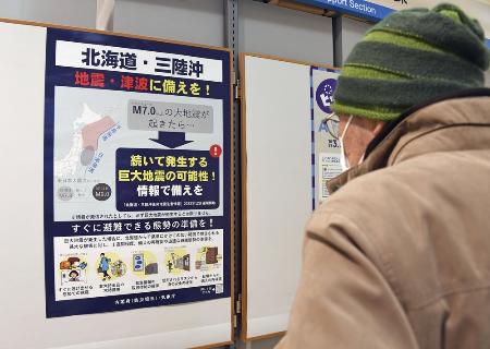 巨大な後発地震への注意を呼びかけるポスターを見つめる人＝２０２２年１２月１６日、青森市