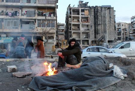 ８日、シリア北部アレッポの路上で火をたいて温まる避難者の男性（ロイター＝共同）