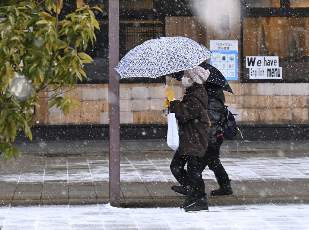 降り始めた雪の中を足早に歩く人たち＝１０日午前８時４０分ごろ、ＪＲ御殿場駅前（東部総局・山川侑哉）