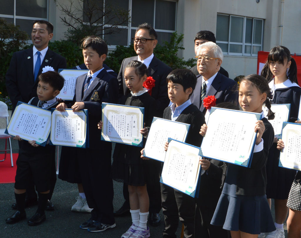 豊田佐吉顕彰祭で、子どもたちと記念写真に納まる章一郎名誉会長（右から３人目）。隣は章男社長＝２０１８年１０月３０日、湖西市立鷲津中