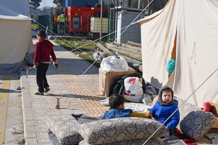 仮設テントの前に座るシリア難民の子どもたち＝１０日、トルコ南部アンタキヤ（共同）