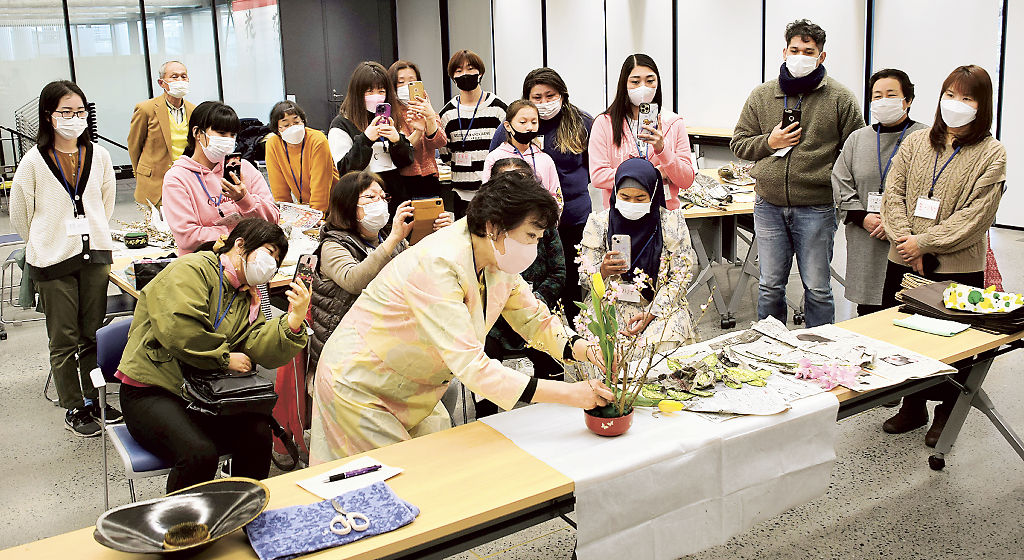 飯塚さん（前列中央）が実践する生け花を見守る参加者＝焼津市役所