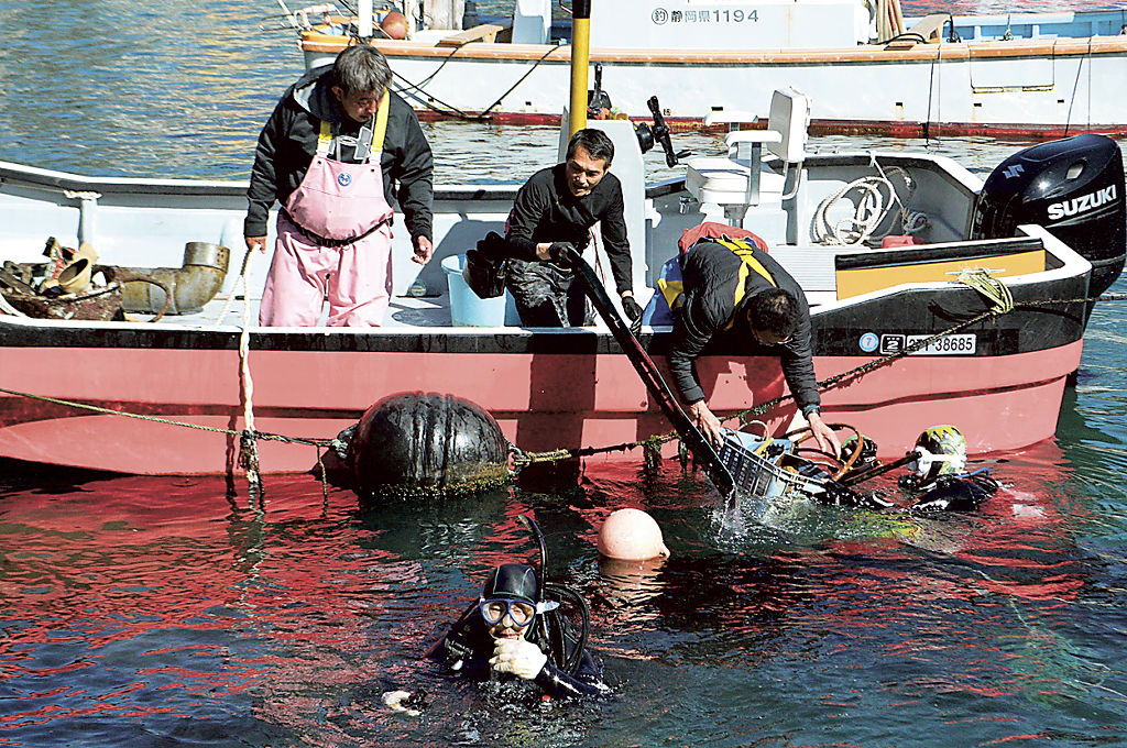 港内に沈んでいた廃棄物を回収するダイバーと漁師＝２１日午前、熱海市の伊豆山港