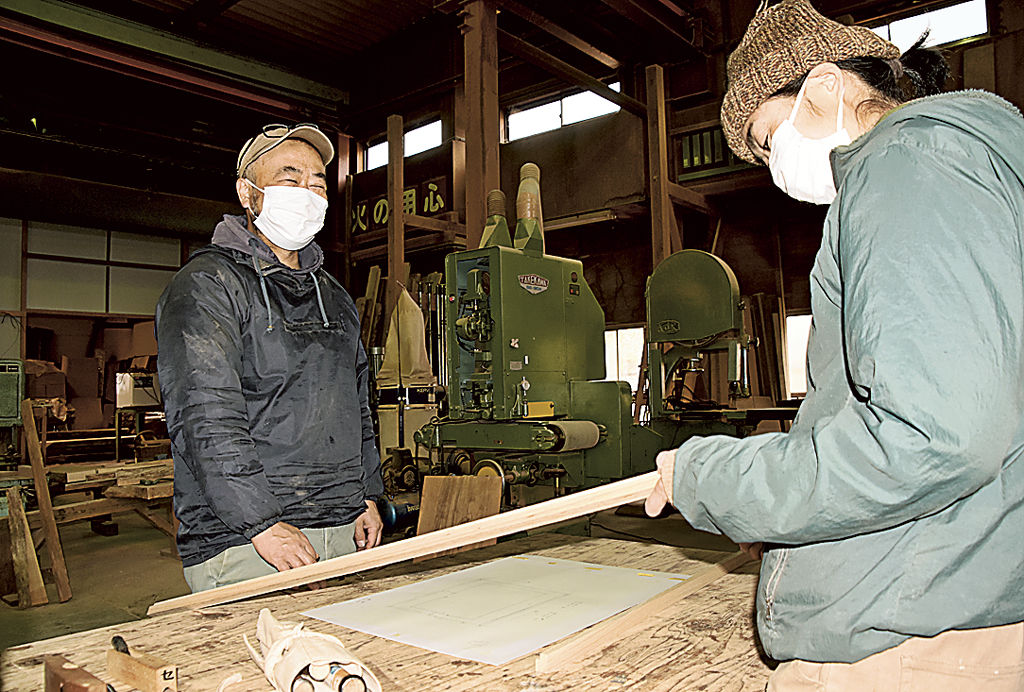 家具の製作に取り組む木工作家を見守る古屋さん（左）＝松崎町峰輪の松崎工房