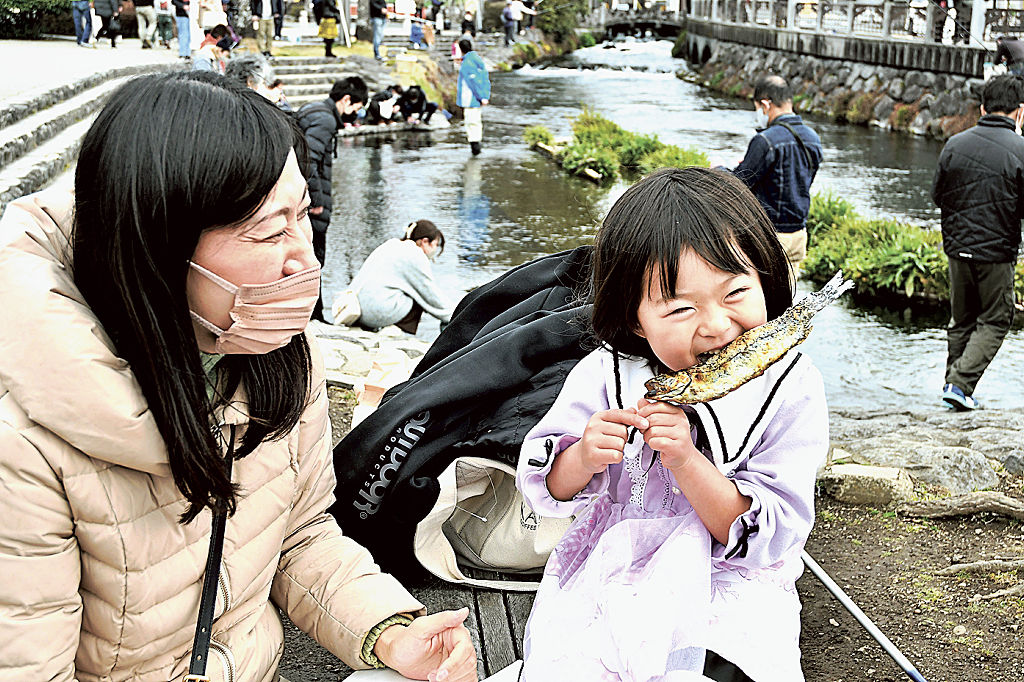 ニジマスの塩焼きをほおばる子ども＝富士宮市の神田川ふれあい広場