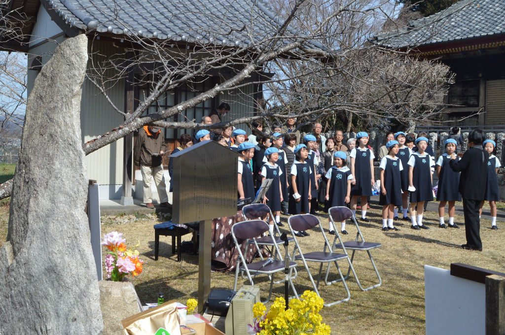 西郷の局の石碑（左）の前で歌う掛川少年少女合唱団＝掛川市掛川の龍華院