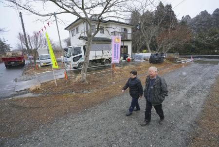 自宅近くを歩く田沢憲郎さん（右）と妻トキイさん。周辺では家屋の解体作業が進み、更地も目立つ＝２月、福島県大熊町