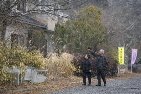 自宅近くを歩く田沢憲郎さん（右）と妻トキイさん。周辺では家屋の解体作業が進み、更地も目立つ＝２月、福島県大熊町