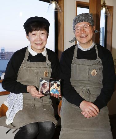 カフェ「ノースライト」を経営する江原正明さん（右）とチエコさん夫妻。手には亡くなった長男一平さんの写真＝２０２２年１２月２０日、東京都北区