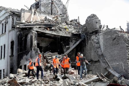 破壊された劇場でがれきを取り除く人たち＝２０２２年４月２５日、ウクライナ南東部マリウポリ（ロイター＝共同）