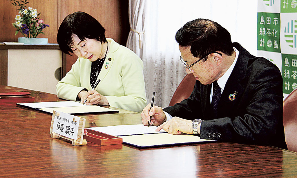 遺贈に関する協定書に署名する染谷市長と伊藤理事長（右）＝島田市役所