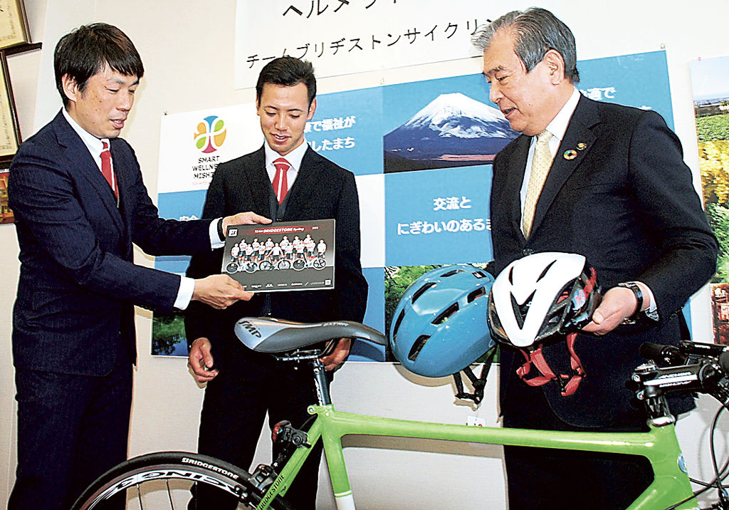 ヘルメットを豊岡市長（右）に贈り、着用の重要性を伝えた宮崎監督（左）と山本選手＝三島市役所