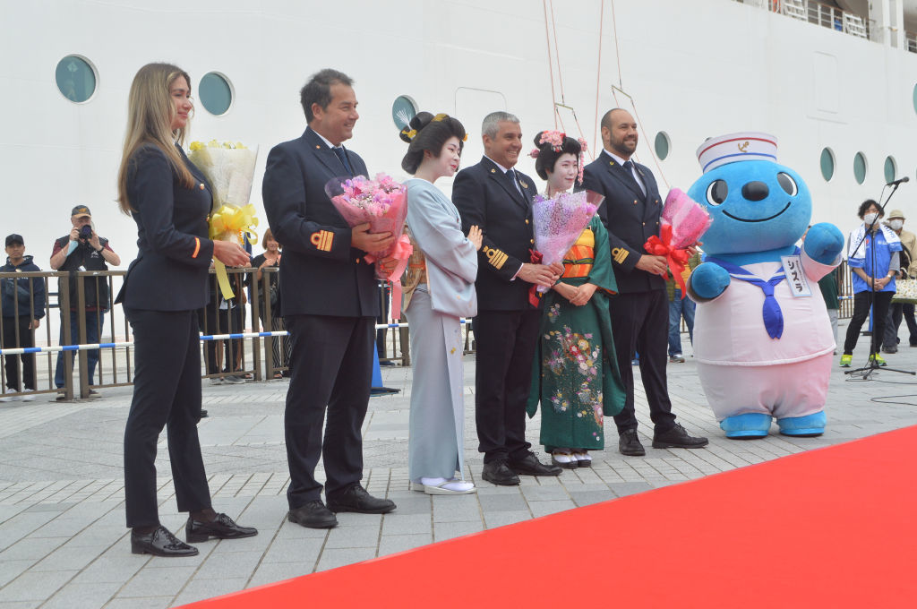 歓迎式典で花束を渡した清水芸妓とポーズするＭＳＣポエジアの乗組員ら＝清水港