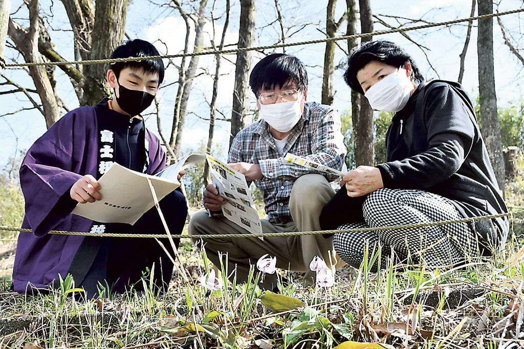 カタクリを観賞する来訪者に生態を紹介する生徒（左）＝富士宮市村山