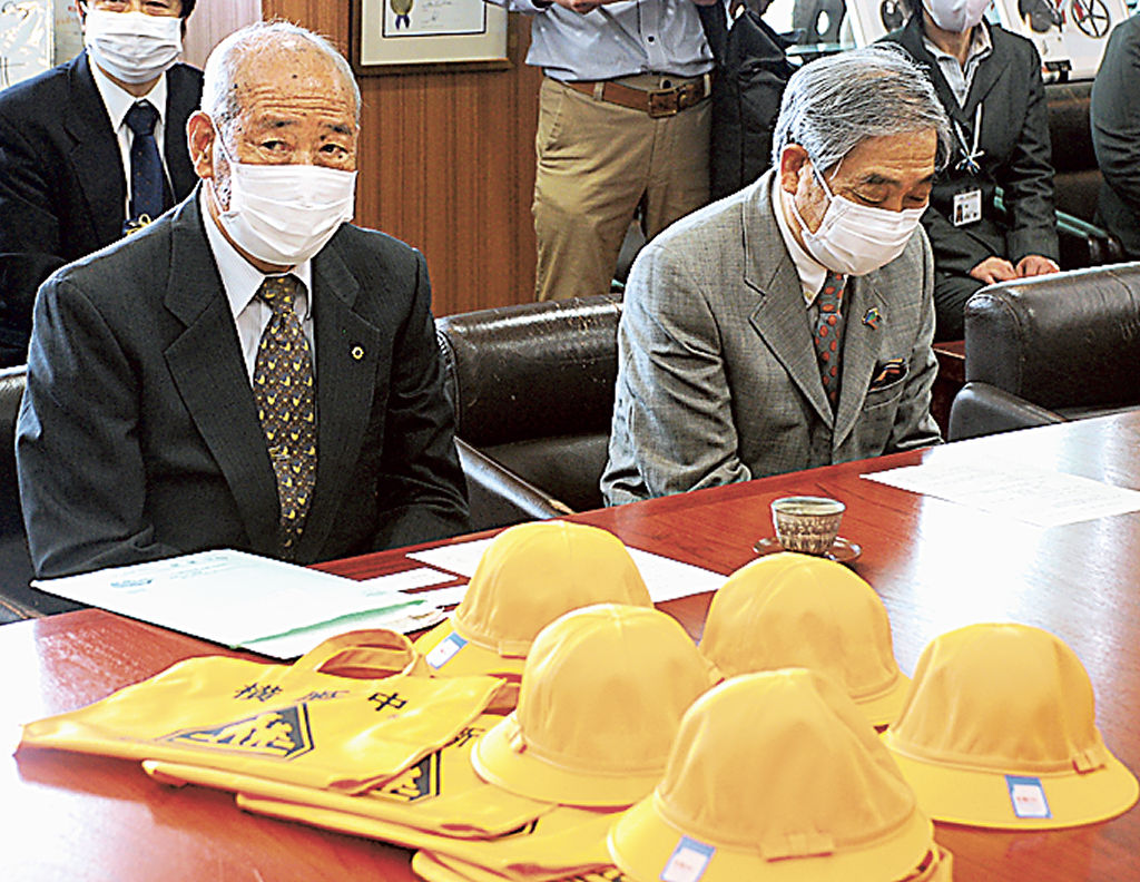 黄色い帽子とバッグを寄贈した佐藤会長（左）＝三島市役所