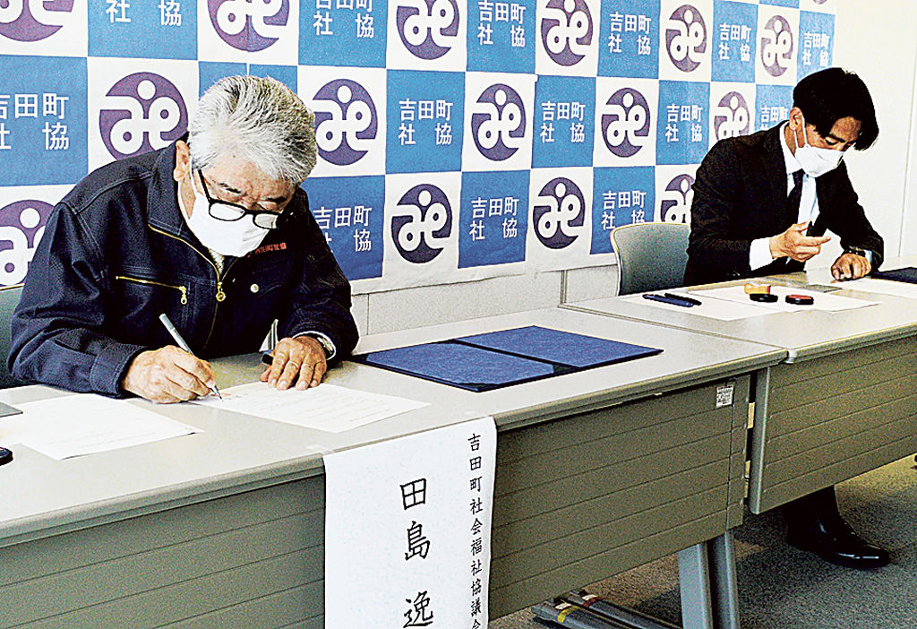 協定書に署名する田島会長（左）と良知青年部長＝吉田町の町健康福祉センター「はぁとふる」