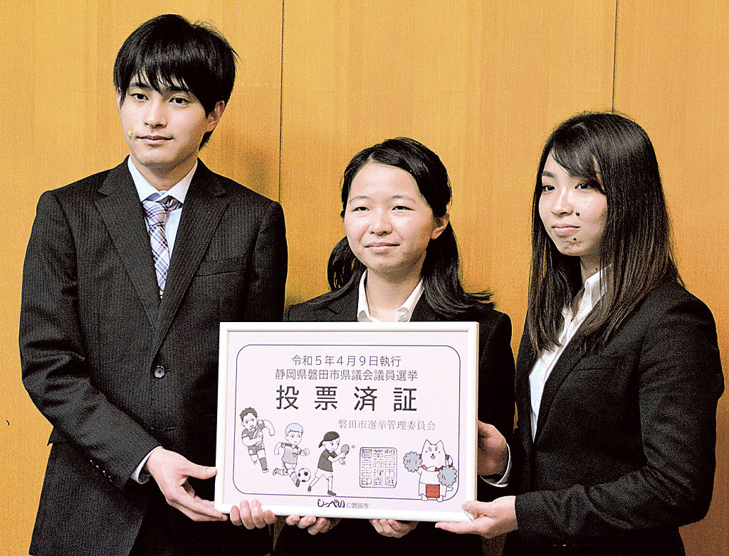 拡大した投票済証のパネルを持つ静岡産業大の学生ら＝磐田市役所