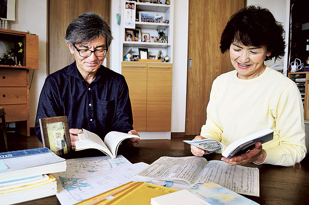 中野祥太朗さんが残したノートを広げ、書籍を確認する裕樹さんと洋子さん＝３月下旬、焼津市内