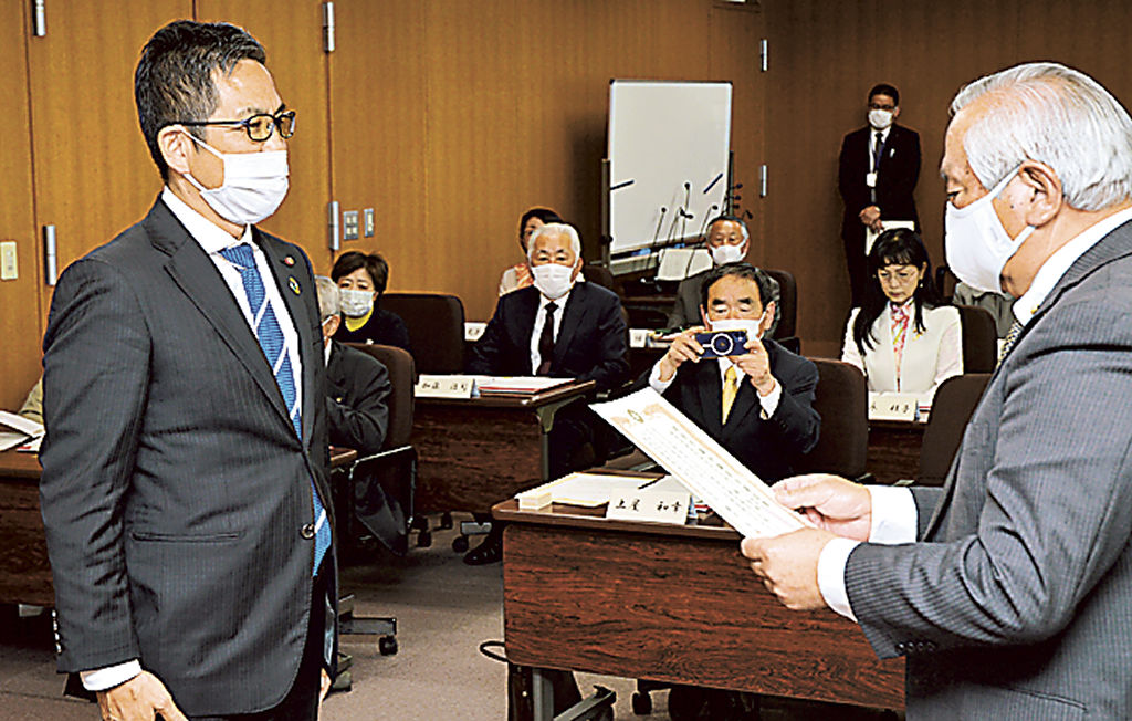 藤井委員長（手前右）から当選証書を受け取る楠氏（同左）＝湖西市役所