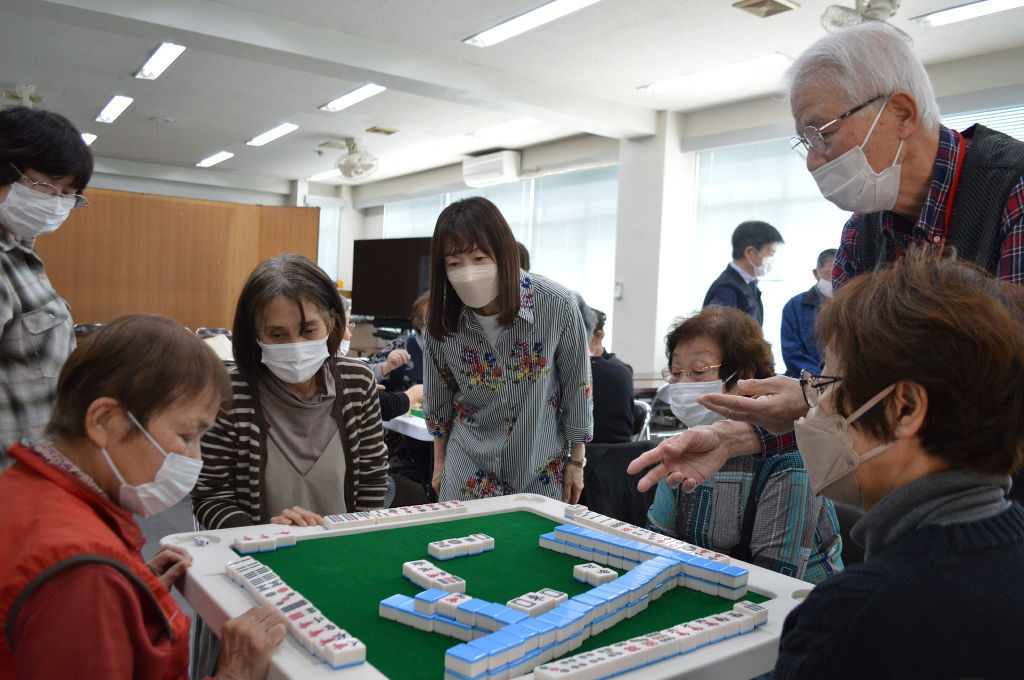 実践を通して健康マージャンのルール説明をする酒井勝武会長（右上）＝４月中旬、沼津市大岡