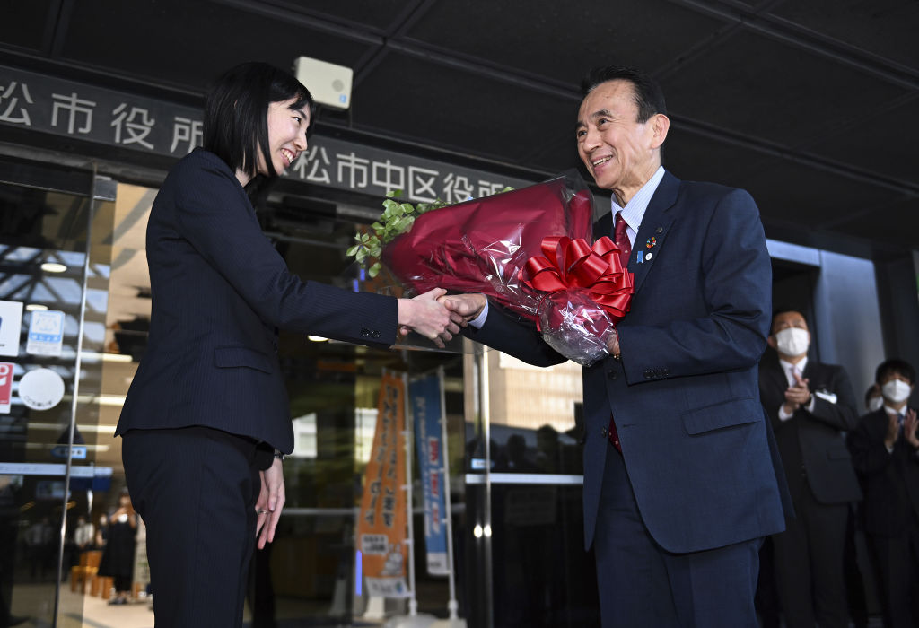 職員から花束を受け取り、握手を交わす鈴木康友市長（右）＝２８日午後、浜松市役所