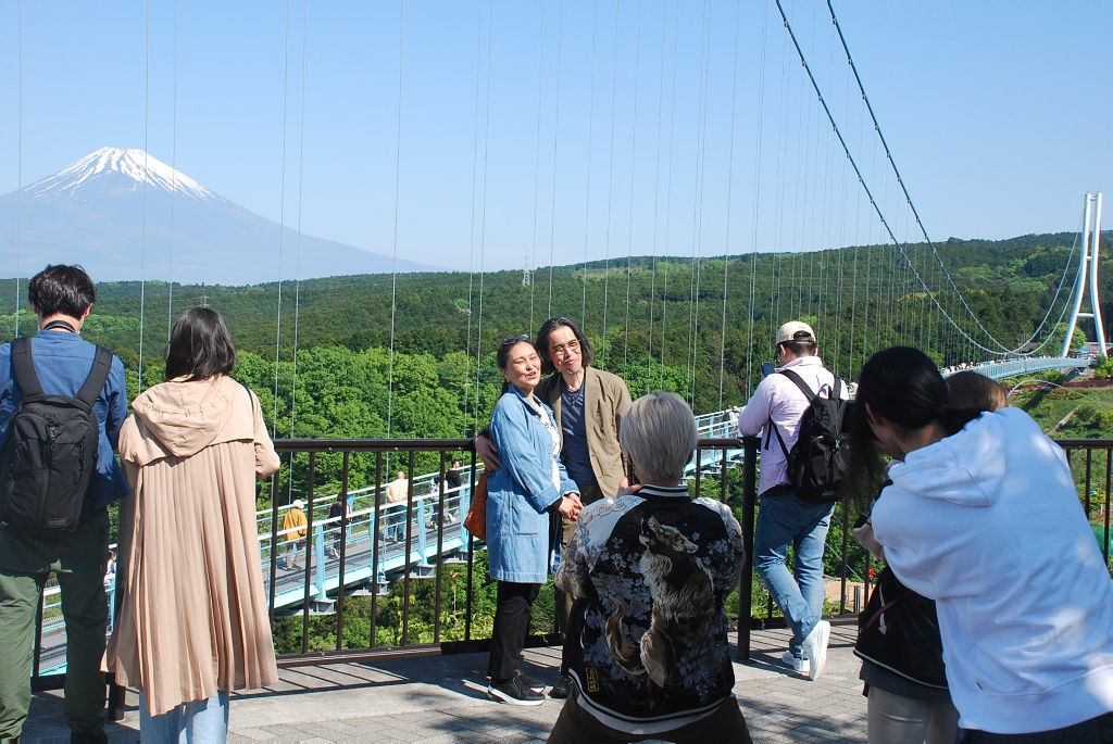 富士山を背景に写真撮影を楽しむ観光客＝３日午前、三島市の三島スカイウオーク