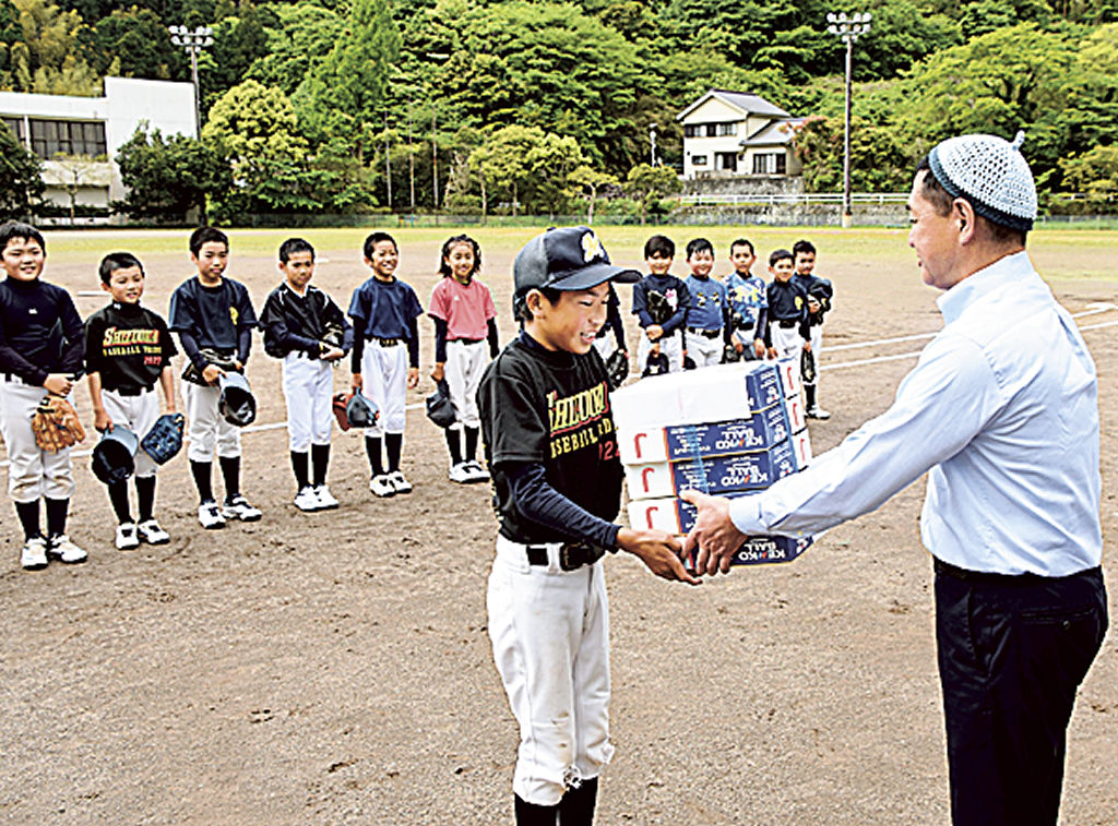 軟式ボールを代表児童に渡す端山会長（右）＝松崎町道部の町営野球場