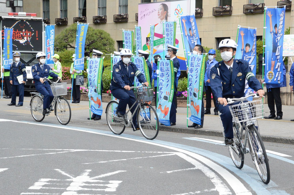 ヘルメットを着用し、自転車で街頭啓発へ出発する警察官＝１１日午前１０時半ごろ、県庁前