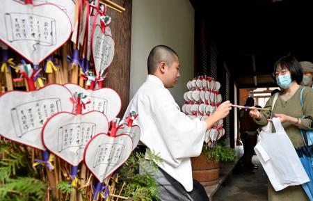 奈良市の唐招提寺で、うちわを手渡す僧侶＝１９日午後