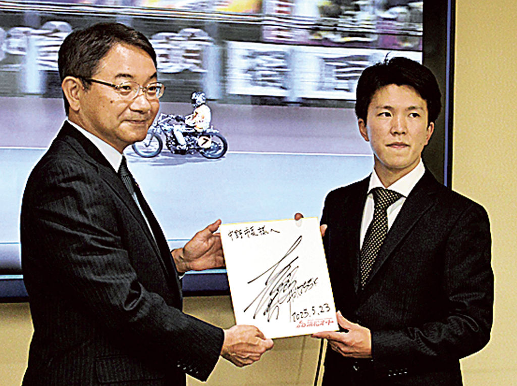 レース映像の前で中野市長（左）にサインを手渡し、優勝を報告する鈴木選手＝浜松市役所