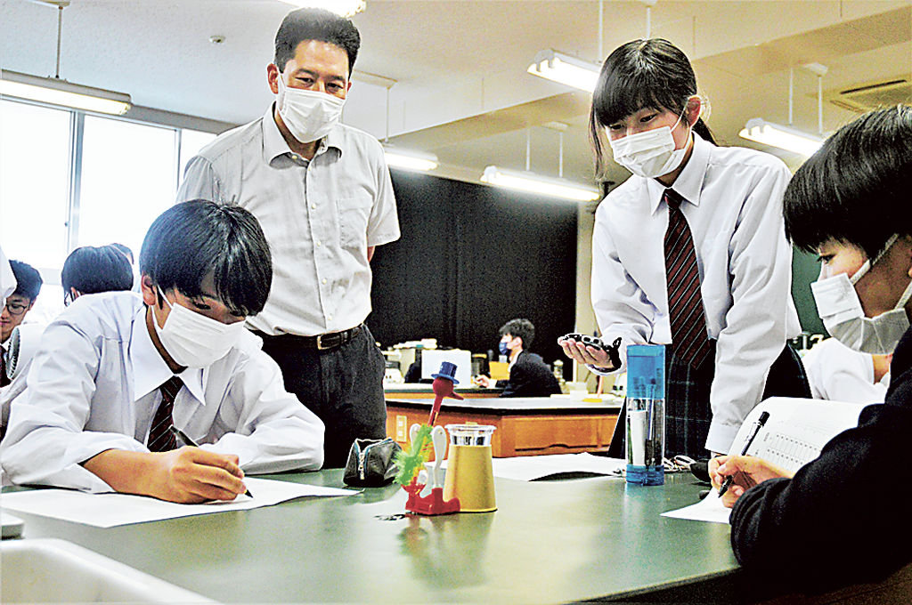 益子准教授（左から２人目）が見守る中、水飲み鳥を使った実験をする生徒＝浜松市中区