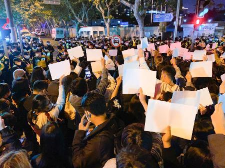 中国上海市中心部で「ゼロコロナ」政策に反対し、当局への抗議を意味する白い紙を掲げる人たち＝２０２２年１１月