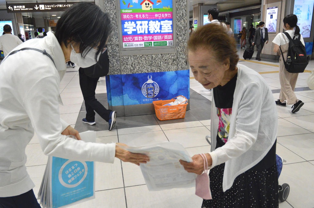 啓発チラシを手渡す浜松市職員（左）＝ＪＲ浜松駅