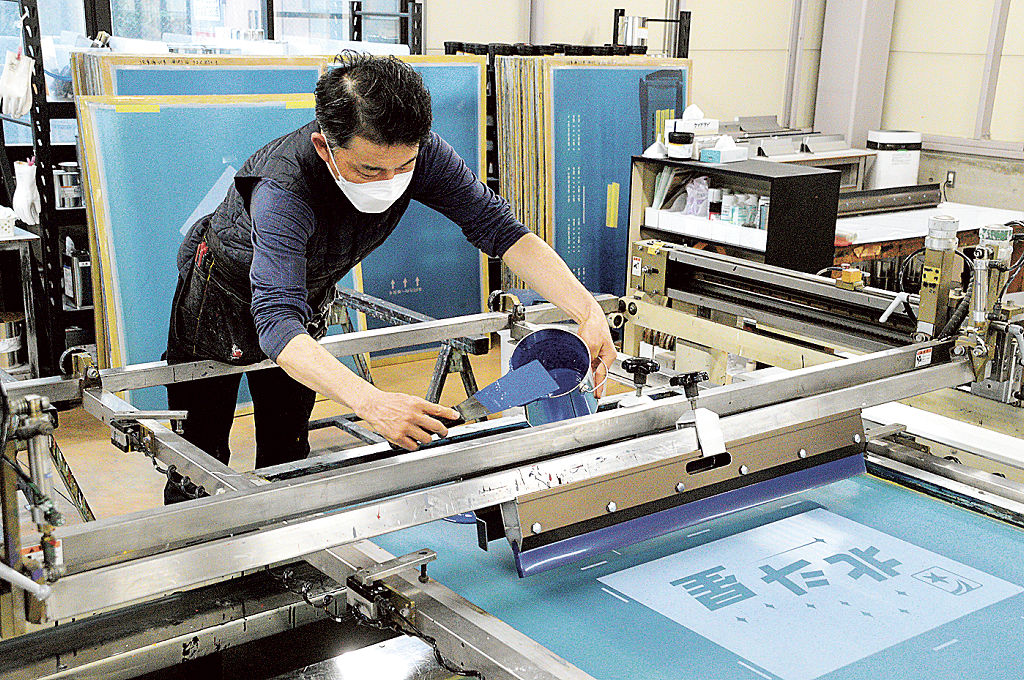 印刷するインクを機械にセットする鈴木利幸さん＝長泉町南一色のコロナ宣広社静岡工場