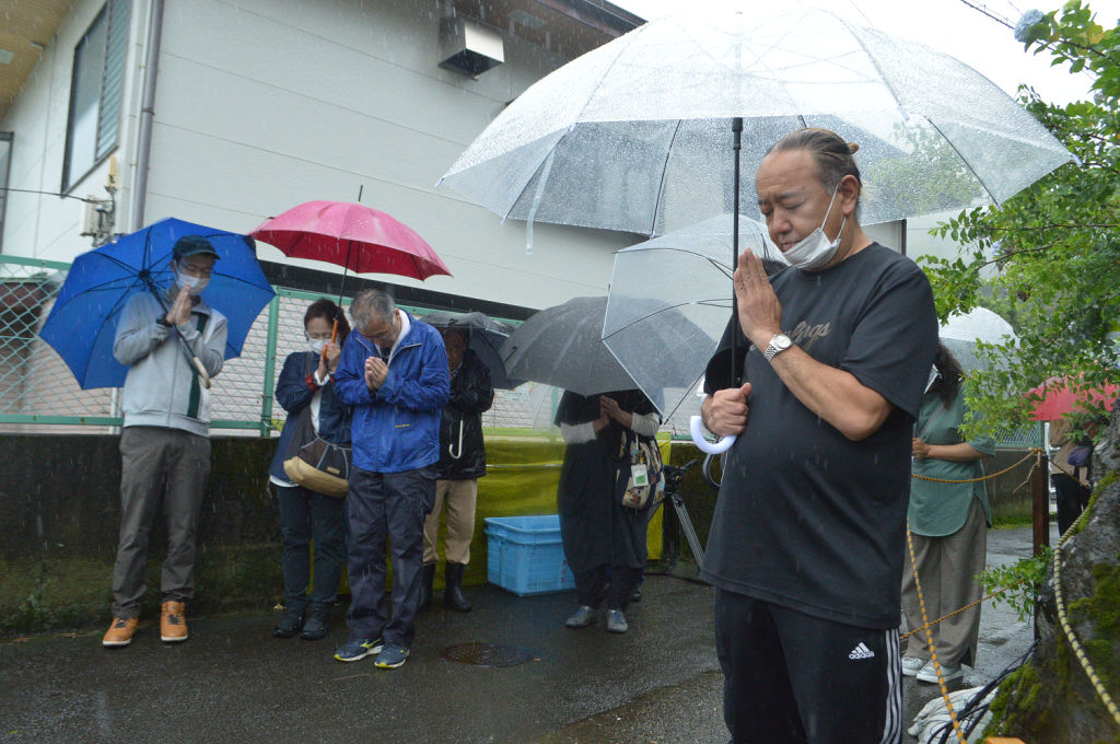 雨の中で犠牲者に黙とうをささげる被災者＝３日午前、熱海市伊豆山
