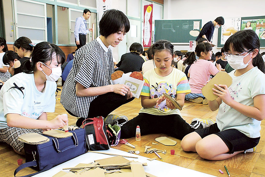 見本を手に児童へ作り方を教える木村さん（左から２人目）＝三島市緑町の西小